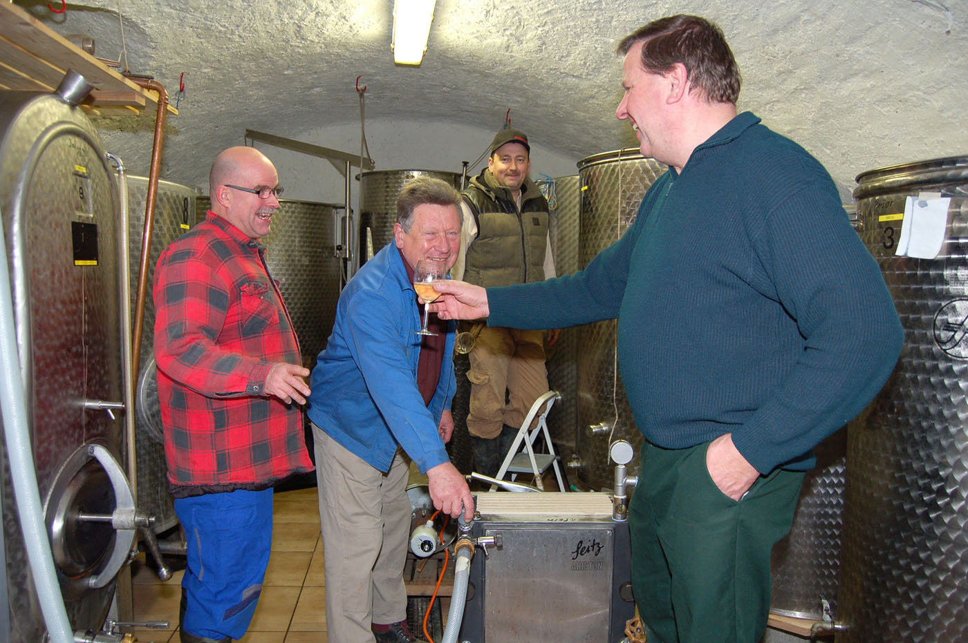 Winzer im Weinkeller freuen sich über den neuen Wein.